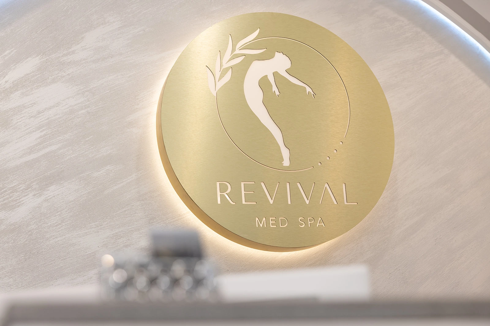 The gold Revival Med Spa emblem