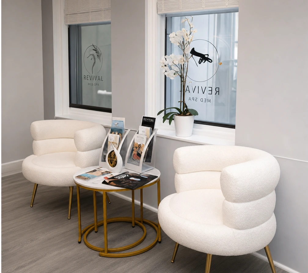 White lounge chairs and an orchid beside the window at Revival